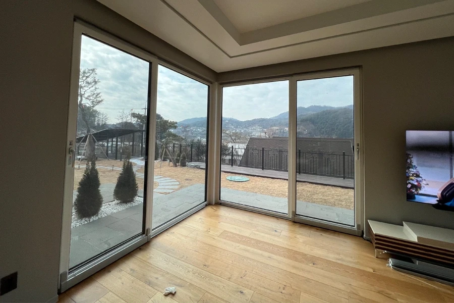 거실 코너 대형 창호로 보이는 산과 마을 풍경