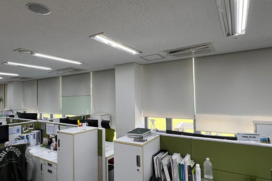 롤 블라인드가 설치된 사무공간 창문과 천장형 공조기